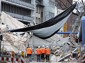 Firemen spead a massive tarp over rubble