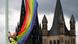 A rainbow flag being hung in front of a cathedral