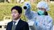 An official wears protective clothing as she scans a man for radiation at an emergency center in Japan