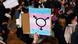 A protest sign with a transgender symbol and flag on it